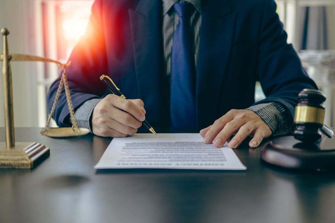 Person signing a document with legal tools.