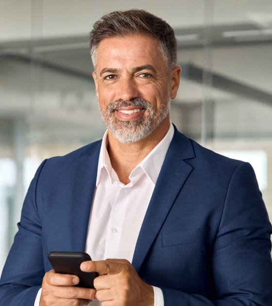 Smiling businessman holding a smartphone.